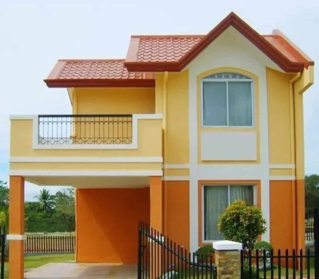 Casa de dos plantas con fachada pintada en amarillo, naranja y blanco