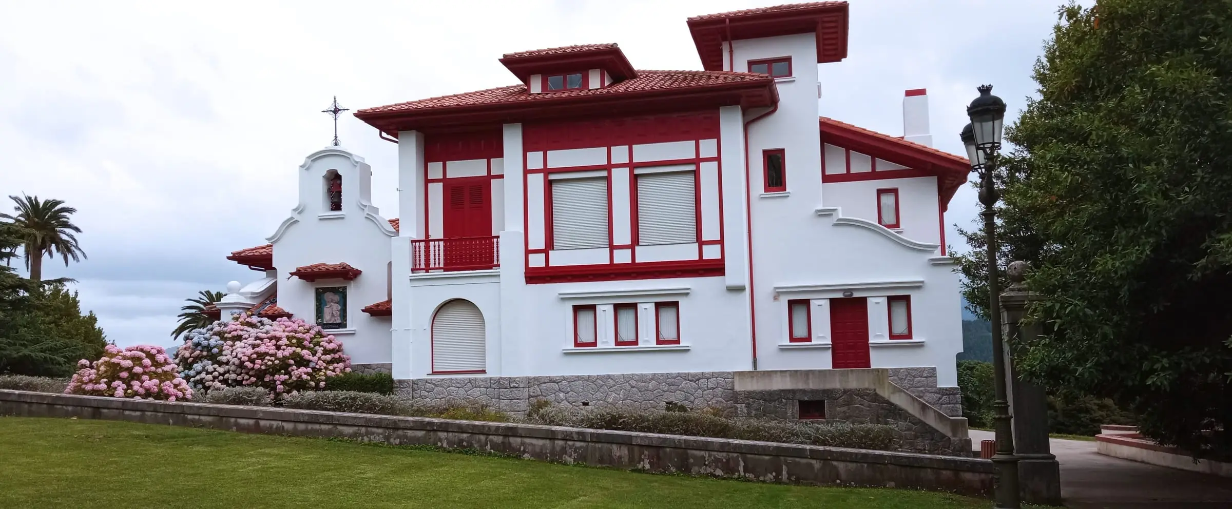 Casa señorial pintada de blanco con carpintería y detalles en rojo