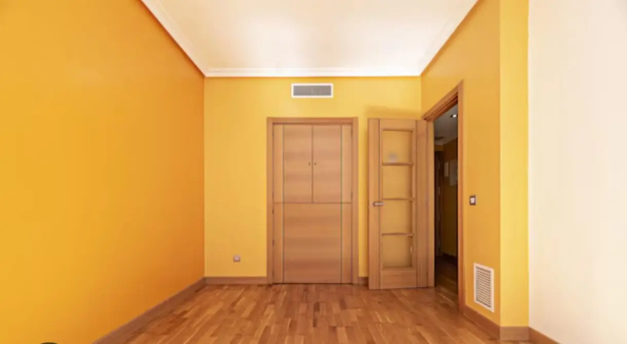 Habitación pintada en amarillo intenso con puertas de madera