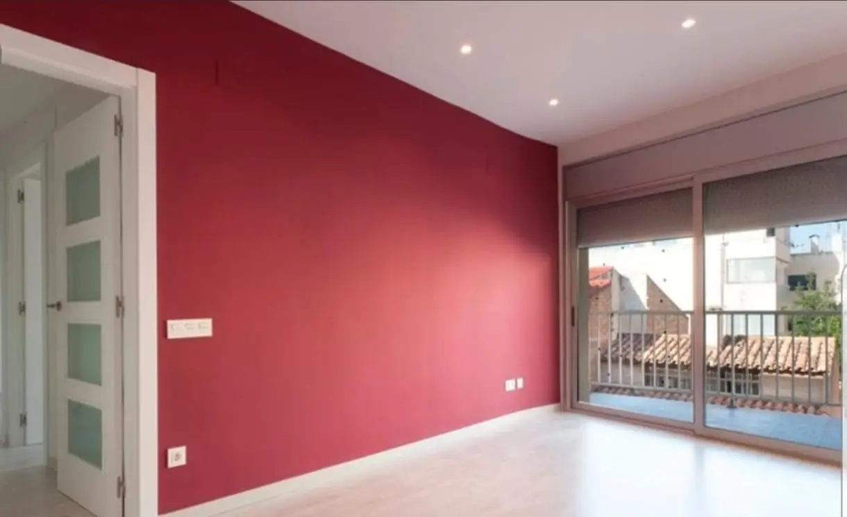 Salón con una pared pintada en color burdeos y suelo de madera clara